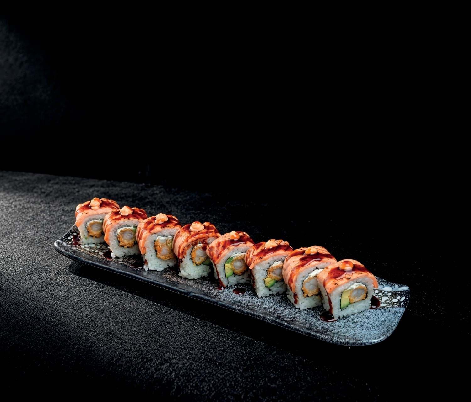 L'Ikko Impérial : une rangée de pièces au saumon braisé et à la crevette tempura, sur un plat long en céramique