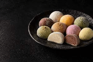 Des mochis de plusieurs couleurs sur une assiette sombre