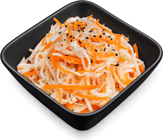Une salade de chou et de carottes râpés, parsemée de sésame, dans un bol carré noir